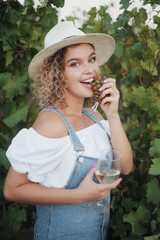 young woman with glass and grapes posing in vineyard