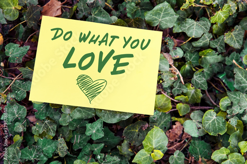 Do what you love concept written on paper on green leaf background. Inspirational quote for motivation, happiness or success in business or life.