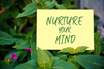 Nurture your mind motivational quote written on paper on green garden background. The effect of thoughts on mind and body concept.