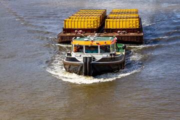 Tug barge towing containers on London's river Thames