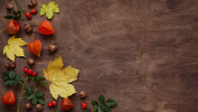Yellow Autumn Leaves, Red Rose Hips, Orange Fezalis And Acorns On Old Brown Wooden Background, Top View, Flat Lay, Copy Space. Autumn Atmosphere Concept