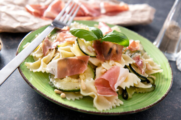 Wall Mural - Tasty farfalle pasta with courgette, prosciutto ham, grana padano cheese and pine nuts