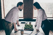 © deagreez - Profile photo of two colleagues have misunderstanding disagreement conflict stand in modern work station place face to face lean hands on table only one boss promotion office indoors