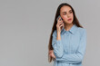 © Bitmap - Cheerful young woman talking on mobile phone isolated on a gray background