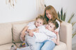 © Roman - Mom hugs her kids while resting on the couch.