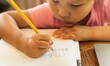 © globalmoments - A young child learning how to write letters and alphabets, pencil and paper. School work.