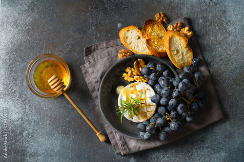 Cuadros en Lienzo Roast camembert and honey with black grapes and baked slice of bread on dark bac