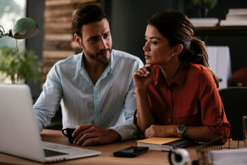 Businessman and businesswoman in office. Businesswoman and businessman working on lap top..