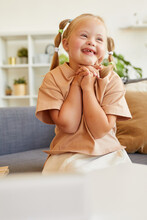 Vertical Portrait Of Cute Girl With Down Syndrome Laughing Happily While Sitting On Couch In Sunlit Room