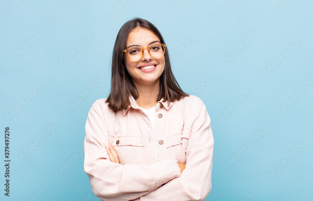 young pretty woman looking like a happy, proud and satisfied achiever smiling with arms crossed - obrazy, fototapety, plakaty 