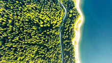 Aerial View Of Evergreen Trees, Texture Of The Top Of The Tree On The Shore Of A Mountain Lake And A Country Road In The Forest. Beautiful Green Spruce Forest. Lake, Pines Aerial View