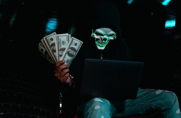 Hacker holding money and using laptop for hacking data