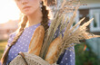 A young beautiful woman with a baguette and wheat in her hands.