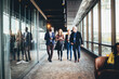 © Maskot - Smiling female and male colleagues walking in office corridor