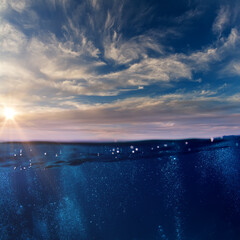 Wall Mural - cloudy sky with the sun splitted by waterline to underwater and air parts as design template