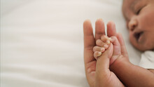 African American New Born Baby Hand Holding Mom Finger On White Bed
