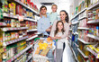 © JackF - Positive parents with two kids and purchases in shopping cart in hypermarket