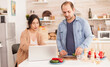 © DC Studio - Couple prepares healthy salad looking at online recipe on laptop in kitchen. Man helping woman to prepare healthy organic dinner, cooking together. Romantic cheerful love relationship
