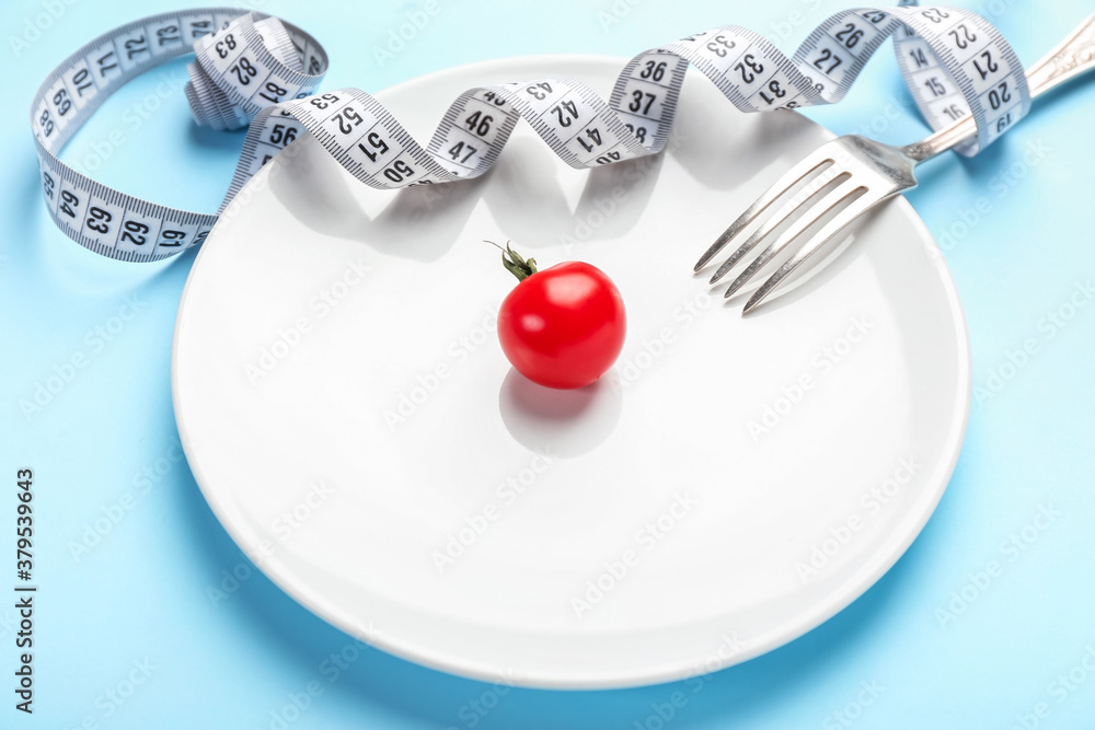 Plate with measuring tape, tomato and fork on color background. Concept of anorexia