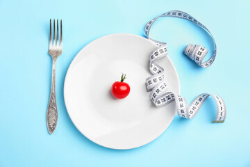 Wall Mural - Plate with measuring tape, tomato and fork on color background. Concept of anorexia