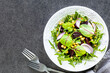 Fresh vegetable salad with beets, arugula, red onion, sorrel in a white plate on a black background. Top view