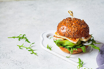 Grilled halloumi burger with slices of avocado and arugula, copy space. Vegetarian food concept.