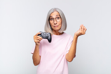 Wall Mural - middle age woman making capice or money gesture, telling you to pay your debts!. playing console concept