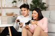 © Prostock-studio - Chinese Boyfriend And Girlfriend Playing Video Games Sitting At Home