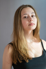 Close up portrait of a pretty teenage girl with long natural blonde hair and smooth skin looking at the camera. Studio shot