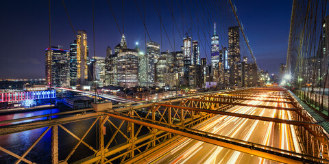 Wall Mural - Panoramic view on Lower Manhattan skyscrapers at Dusk and Brooklyn Bridge with light trails. Evening in New York City, NY, USA