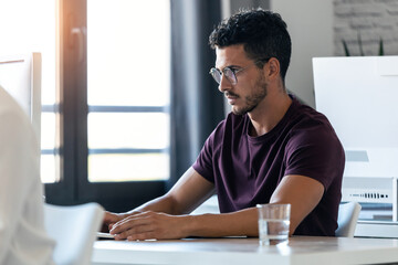 Handsome young entrepreneur working with the computer in the office.