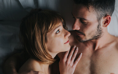 Romantic couple of lovers cuddling in the bed at home. Boyfriend and girlfriend in love.