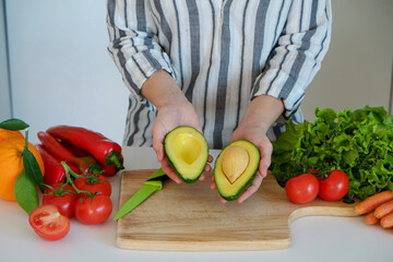 Cropped shot of unrecognizable woman cutting various fruits, vegetables, herbs and greens at her kitchen. Professional cook slicing ingredients. Vegan food concept. Close up, copy space, background.