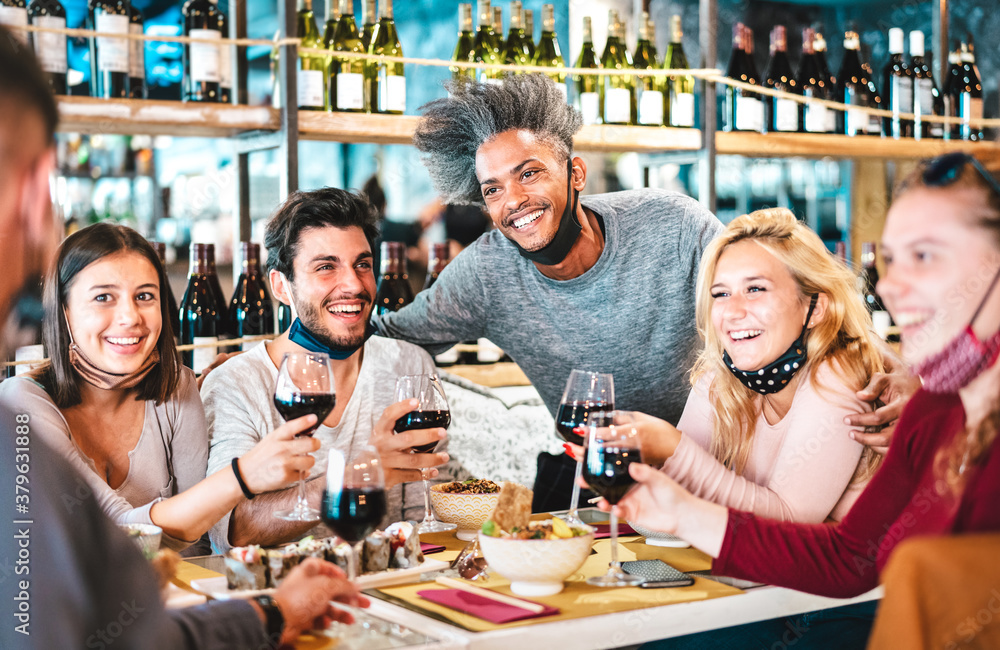 Friends drinking red wine at sushi bar restaurant with open face masks - New normal lifestyle concept with happy people having fun together on vivid filter - Focus on afroamerican guy - obrazy, fototapety, plakaty 