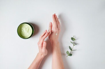 Wall Mural - Revitalizing hand cream for healing and recovery after excessive use of soap and disinfectants. Young woman applying moisturizing lotion. Copy space, close up, pink background, flat lay, top view.