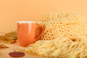Wall Mural - Woolen scarf with cup of tea and autumn leafs on beige background