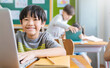 Portrait of Asian little boy using computer to learn lessons in elementary school. Student boy studying in primary. Children with gadgets. Education knowledge, technology internet network concept