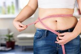 Fototapeta Panele - Female fat figure with measuring tape on blur background