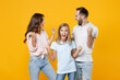 © ViDi Studio - Excited parents mom dad with child kid daughter teen girl in basic t-shirts clenching fists doing winner gesture isolated on yellow background studio portrait. Family day parenthood childhood concept.