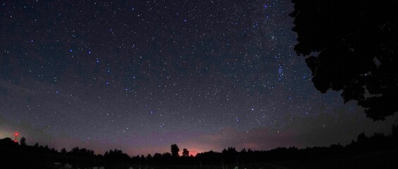blue dark night sky with many stars. night sky over rural landscape. high iso landscape with fisheye