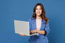 Smiling Cheerful Beautiful Attractive Young Brunette Woman 20s Wearing Basic Jacket Standing Working On Laptop Pc Computer Looking Camera Isolated On Bright Blue Colour Background Studio Portrait.
