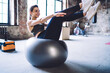 © BullRun - Smiling caucasian slim woman sitting on fitball working on abdominal muscles enjoying healthy lifestyle, cheerful female in active wear working on slimming and perfect body shape in modern gym