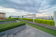 © tampatra - Sky garden on private rooftop of condominium or hotel, high rise architecture building with tree, grass field, and blue sky.