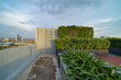 © tampatra - Sky garden on private rooftop of condominium or hotel, high rise architecture building with tree, grass field, and blue sky.