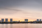 Fototapeta  - modern city along a river at sunset, panoramic view, golden hour