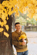 © anatoliycherkas - Handsome and happy guy with a bouquet of yellow leaves smiling and drinking coffee in autumn park