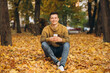 © anatoliycherkas - Portrait of handsome and happy boy smiling and drinking coffee in the autumn park