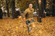 © anatoliycherkas - Handsome and happy guy smiles and runs scattering yellow leaves in autumn park