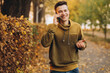 © anatoliycherkas - Portrait of handsome and happy guy smiling and talking on the phone in the autumn park