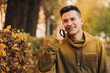 © anatoliycherkas - Portrait of handsome and happy guy smiling and talking on the phone in the autumn park